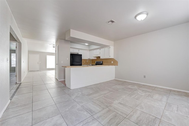 201 Kathleen Dr, Midwest City, OK 73110 - kitchen with freestanding refrigerator, white cabinetry, open floor plan, and under cabinet range hood