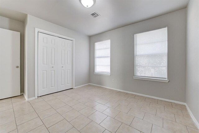 201 Kathleen Dr, Midwest City, OK 73110 - unfurnished bedroom with light tile patterned flooring, a closet, and baseboards