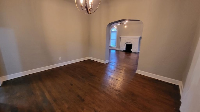 929 NE 21st St, Oklahoma City, OK 73105 - unfurnished dining area featuring arched walkways, dark wood-style floors, a chandelier, and baseboards