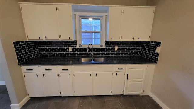 929 NE 21st St, Oklahoma City, OK 73105 - kitchen featuring dark countertops, a sink, baseboards, and white cabinets