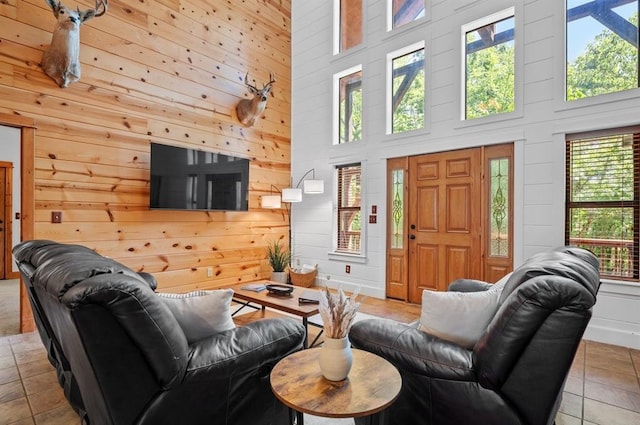 83 Bobber Rd, Broken Bow, OK 74728 - living room featuring plenty of natural light, tile patterned flooring, a towering ceiling, wooden walls, and baseboards