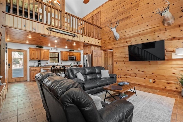 83 Bobber Rd, Broken Bow, OK 74728 - living room featuring wooden walls, a high ceiling, and light tile patterned floors