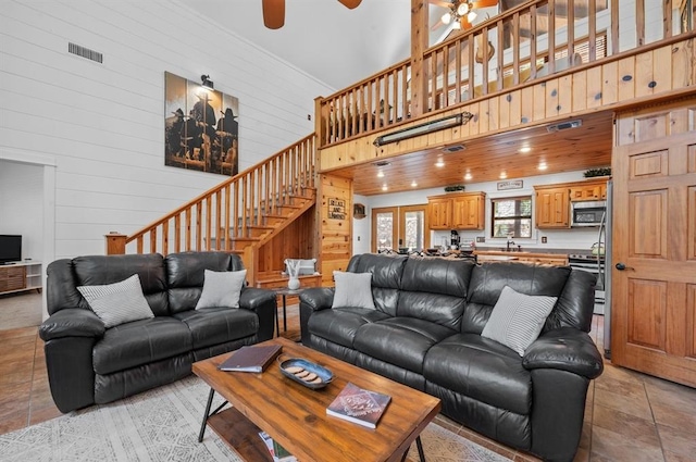 83 Bobber Rd, Broken Bow, OK 74728 - living room with a ceiling fan, stairs, a high ceiling, wood walls, and light tile patterned floors
