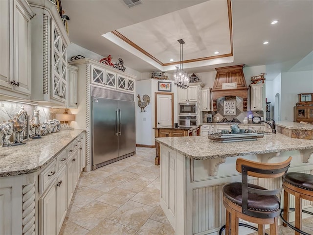 3122 Thornbrooke Blvd, Edmond, OK 73013 - kitchen with built in appliances, a raised ceiling, tasteful backsplash, a spacious island, and a kitchen bar