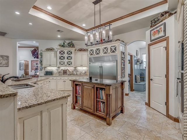 3122 Thornbrooke Blvd, Edmond, OK 73013 - kitchen with stainless steel built in refrigerator, arched walkways, a kitchen island with sink, a sink, and light stone counters