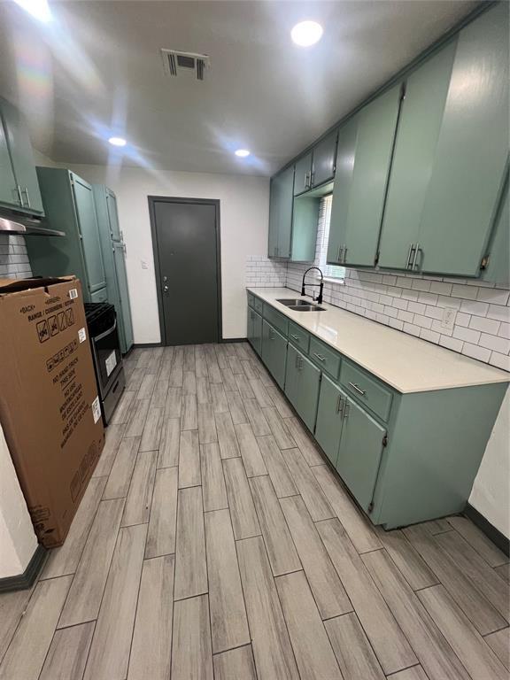 6505 NW 34th St, Bethany, OK 73008 - kitchen featuring green cabinets, wood finish floors, a sink, light countertops, and tasteful backsplash