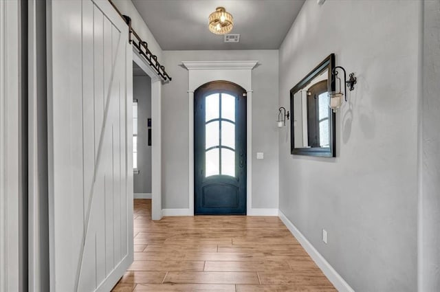 1008 Collis Way, Newcastle, OK 73065 - foyer entrance featuring a barn door, light wood-style flooring, and baseboards