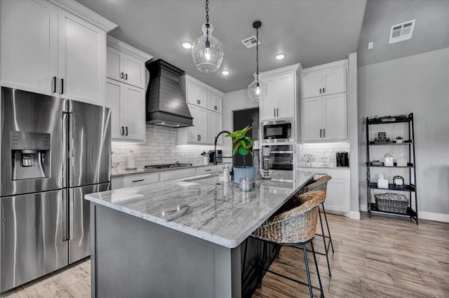1008 Collis Way, Newcastle, OK 73065 - kitchen with stainless steel appliances, premium range hood, decorative backsplash, light stone countertops, and white cabinets