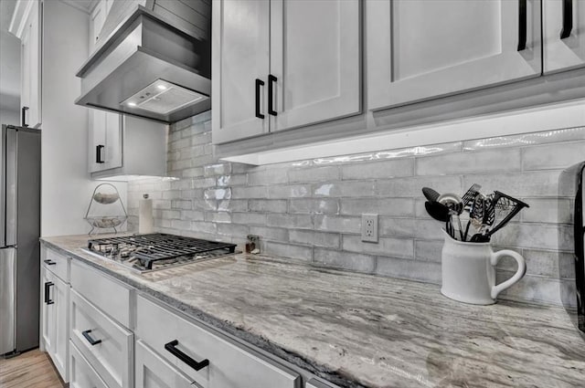 1008 Collis Way, Newcastle, OK 73065 - kitchen featuring wall chimney exhaust hood, stainless steel appliances, tasteful backsplash, light stone countertops, and white cabinetry