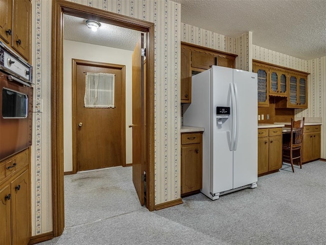 4004 N Shannon Ave, Bethany, OK 73008 - kitchen with wallpapered walls, white refrigerator with ice dispenser, a textured ceiling, light carpet, and brown cabinetry