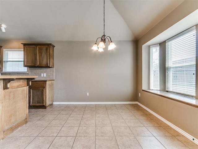 7909 Dawn Cir, Oklahoma City, OK 73135 - kitchen featuring a breakfast bar area, a chandelier, lofted ceiling, backsplash, and hanging light fixtures