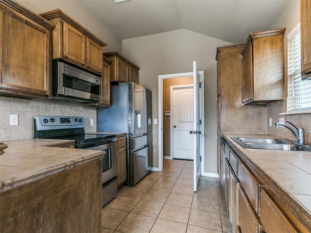7909 Dawn Cir, Oklahoma City, OK 73135 - kitchen featuring stainless steel appliances, a sink, tile countertops, vaulted ceiling, and light tile patterned flooring