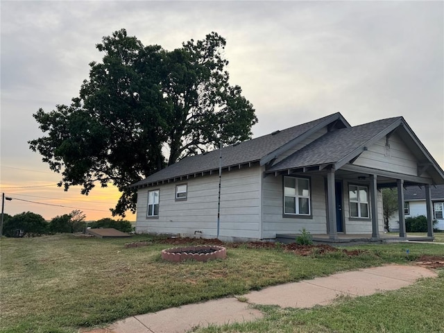 214 N 3rd St, Sentinel, OK 73664 - property exterior at dusk with a porch, a lawn, and a shingled roof