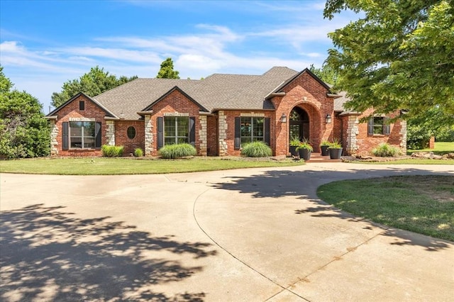 1322 Mockingbird Ln, Guthrie, OK 73044 - view of front of house featuring brick siding, a front yard, curved driveway, and a shingled roof