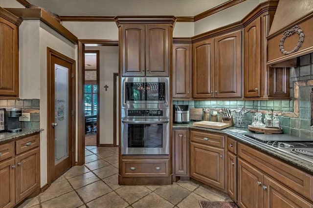 1322 Mockingbird Ln, Guthrie, OK 73044 - kitchen with tasteful backsplash, stainless steel microwave, ornamental molding, light tile patterned floors, and dark stone counters