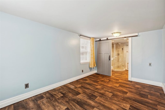 1535 NW 39th St, Oklahoma City, OK 73118 - unfurnished bedroom with baseboards, dark wood-style flooring, and a barn door