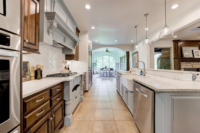 5905 Smoky Hill Trl, Edmond, OK 73034 - kitchen featuring appliances with stainless steel finishes, a sink, arched walkways, tasteful backsplash, and recessed lighting