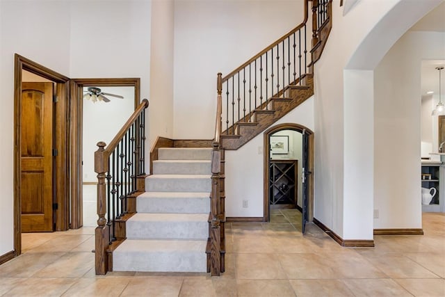 5905 Smoky Hill Trl, Edmond, OK 73034 - staircase with arched walkways, a high ceiling, baseboards, and tile patterned floors