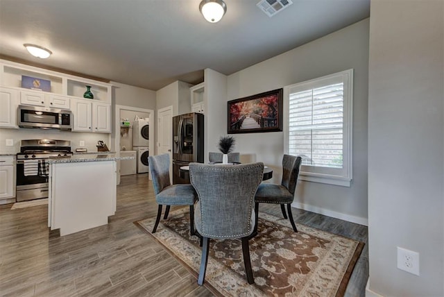 11734 Split Oak Cir, Guthrie, OK 73044 - dining room with stacked washing machine and dryer, wood finished floors, and baseboards