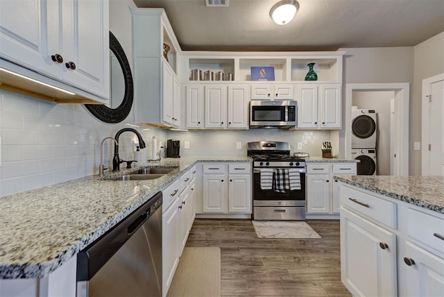 11734 Split Oak Cir, Guthrie, OK 73044 - kitchen featuring appliances with stainless steel finishes, stacked washing machine and dryer, open shelves, a sink, and white cabinets