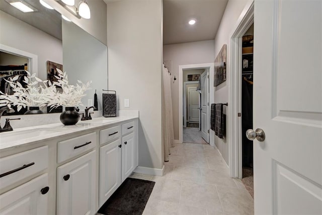 11734 Split Oak Cir, Guthrie, OK 73044 - bathroom with double vanity, a walk in closet, tile patterned flooring, curtained shower, and baseboards