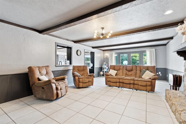 2208 Amber Rd, Oklahoma City, OK 73170 - living room featuring a textured ceiling, a chandelier, beamed ceiling, light tile patterned floors, and wainscoting
