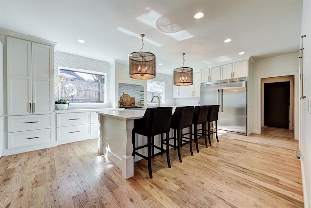 4420 Trophy Dr, Norman, OK 73072 - kitchen with stainless steel built in refrigerator, light countertops, light wood-style flooring, a kitchen breakfast bar, and a center island with sink