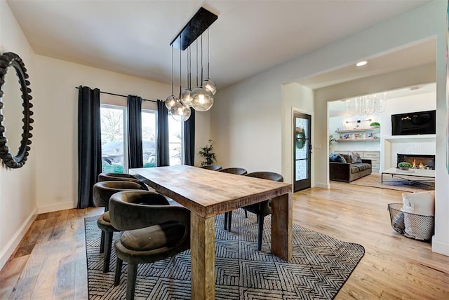4420 Trophy Dr, Norman, OK 73072 - dining area with a chandelier, light wood-style floors, baseboards, and a warm lit fireplace