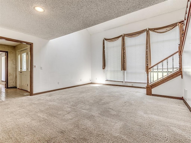 19005 Aerial Rd, Edmond, OK 73012 - unfurnished living room featuring carpet flooring, baseboards, healthy amount of natural light, a textured ceiling, and stairs
