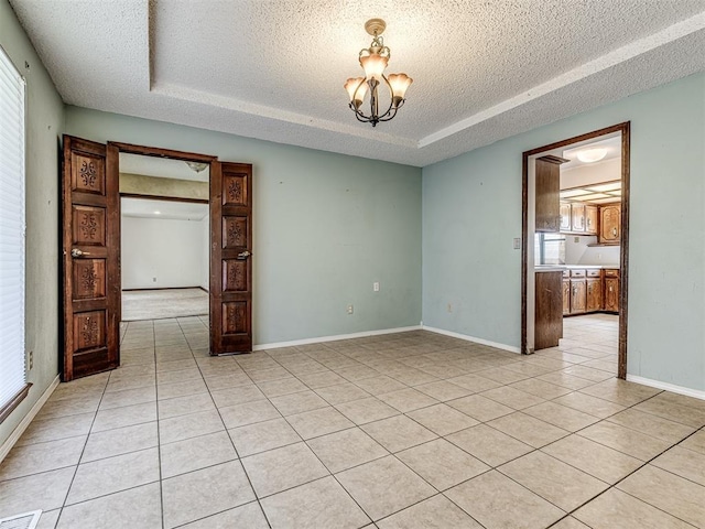 19005 Aerial Rd, Edmond, OK 73012 - spare room with a textured ceiling, a raised ceiling, a chandelier, light tile patterned flooring, and plenty of natural light