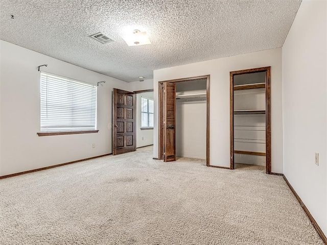 19005 Aerial Rd, Edmond, OK 73012 - unfurnished bedroom with multiple closets, light colored carpet, a textured ceiling, and baseboards
