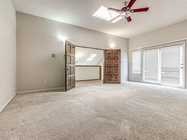 19005 Aerial Rd, Edmond, OK 73012 - carpeted spare room with a textured ceiling, lofted ceiling, a ceiling fan, a skylight, and baseboards