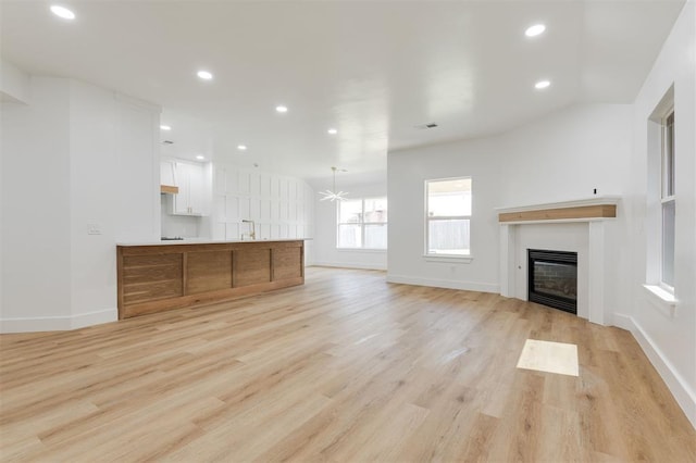 2016 NW 172nd St, Edmond, OK 73012 - unfurnished living room with a glass covered fireplace, light wood finished floors, recessed lighting, baseboards, and a chandelier