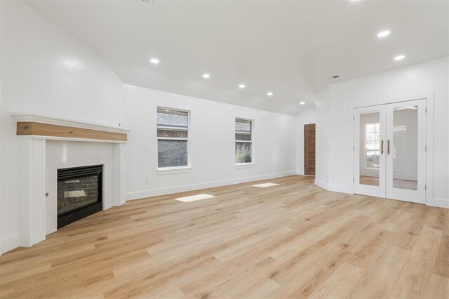 2016 NW 172nd St, Edmond, OK 73012 - unfurnished living room featuring a glass covered fireplace, vaulted ceiling, recessed lighting, light wood-style floors, and french doors