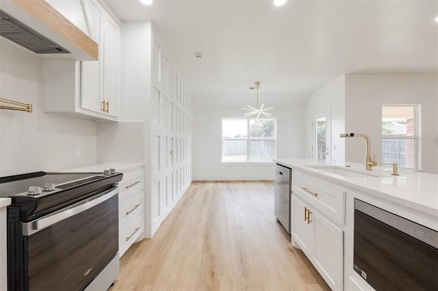 2016 NW 172nd St, Edmond, OK 73012 - kitchen featuring stainless steel appliances, wall chimney exhaust hood, a sink, light countertops, and white cabinetry