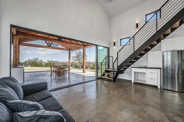 18800 NE 122nd St, Jones, OK 73049 - living room featuring high vaulted ceiling, finished concrete flooring, stairs, and baseboards