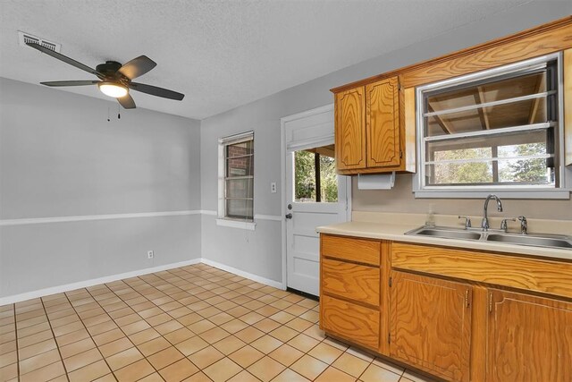 1036 Box St, Altus, OK 73521 - kitchen with a sink, a ceiling fan, light countertops, a textured ceiling, and light tile patterned flooring