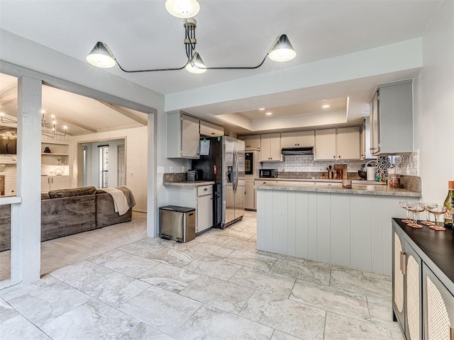 13613 Pin Oak, Edmond, OK 73013 - kitchen featuring a tray ceiling, stainless steel refrigerator with ice dispenser, under cabinet range hood, open floor plan, and tasteful backsplash