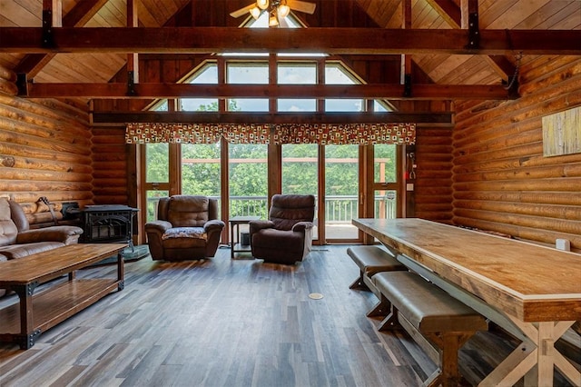 1000 N Canadian Ave, Purcell, OK 73080 - living area featuring log walls, wooden ceiling with exposed beams, a wood stove, high vaulted ceiling, and plenty of natural light