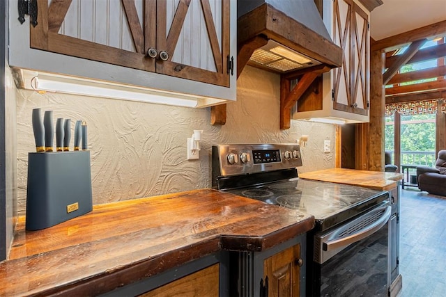 1000 N Canadian Ave, Purcell, OK 73080 - kitchen with stainless steel electric range, custom exhaust hood, wood finished floors, butcher block counters, and a textured wall