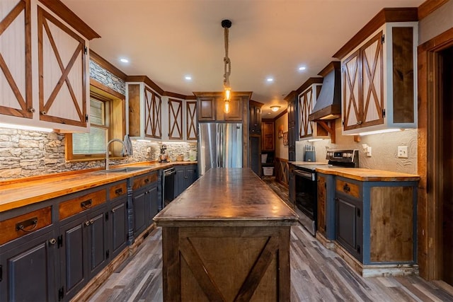 1000 N Canadian Ave, Purcell, OK 73080 - kitchen with butcher block countertops, appliances with stainless steel finishes, a sink, custom range hood, and a center island