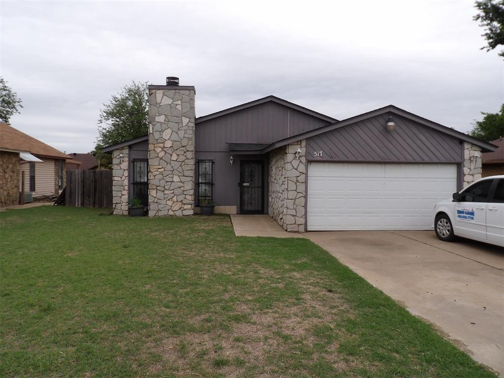 517 NW 115th St, Oklahoma City, OK 73114 - view of front of home featuring concrete driveway, an attached garage, stone siding, and a chimney