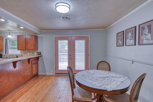 912 E Comanche St, Norman, OK 73071 - dining area with a textured ceiling, french doors, light wood-type flooring, crown molding, and baseboards
