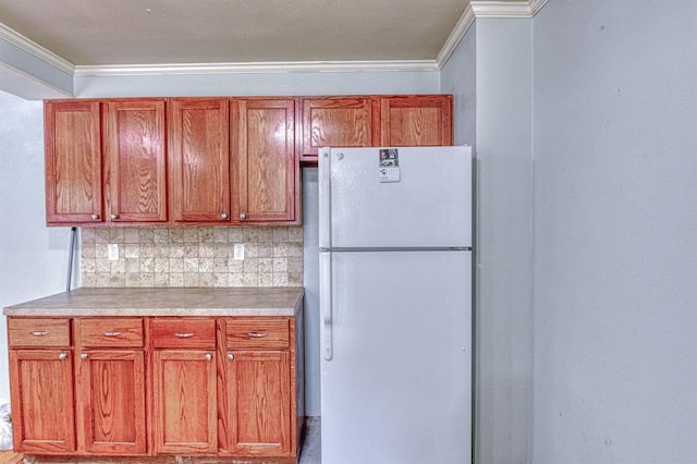 912 E Comanche St, Norman, OK 73071 - kitchen with freestanding refrigerator, crown molding, tasteful backsplash, light countertops, and brown cabinets