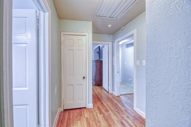 912 E Comanche St, Norman, OK 73071 - hall with light wood-style flooring, a textured wall, baseboards, and attic access