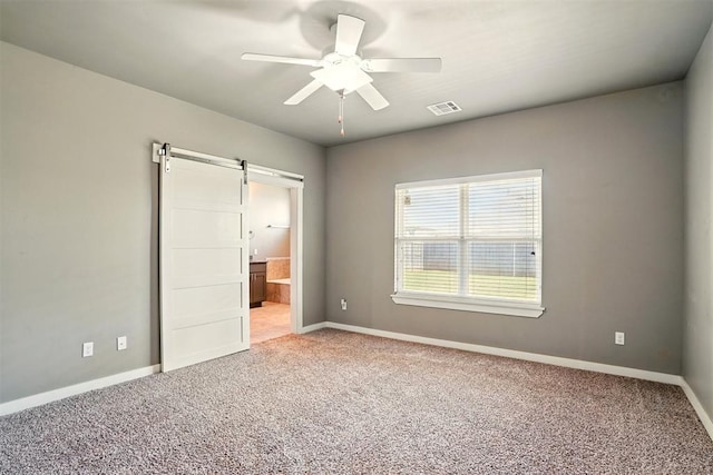 8332 NW 139 Th Ter, Oklahoma City, OK 73142 - unfurnished bedroom featuring a barn door, carpet flooring, baseboards, and connected bathroom