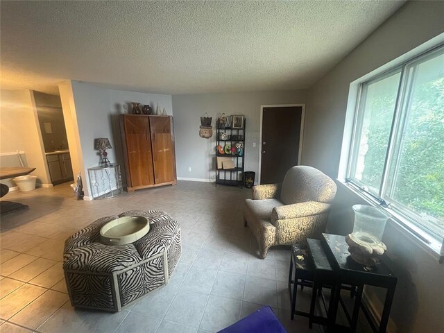 tiled living area with a textured ceiling and baseboards