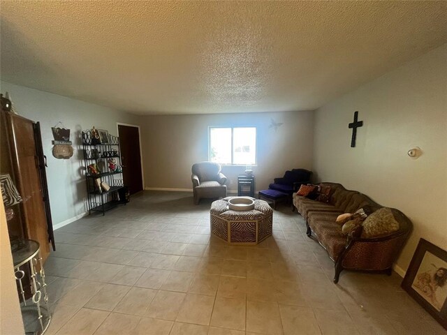 living room with a textured ceiling, light tile patterned flooring, and baseboards