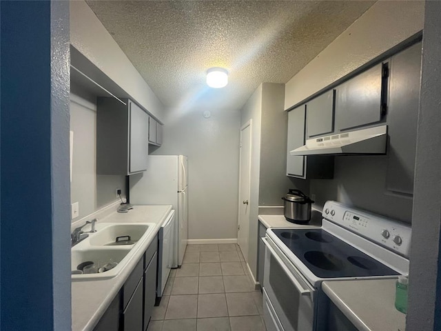 kitchen with white appliances, under cabinet range hood, a sink, a textured ceiling, and light tile patterned flooring