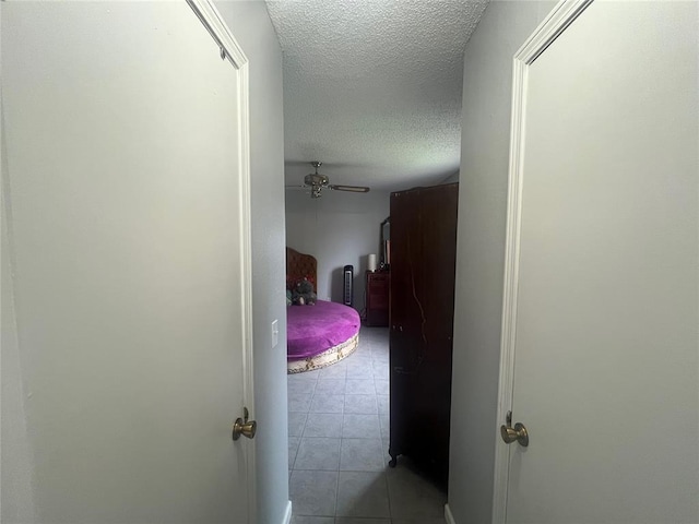 corridor with a textured ceiling and light tile patterned flooring